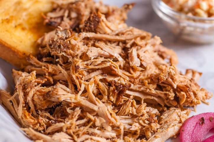 Close up shot of pulled pork fibers in a sandwich freshy served on a platter